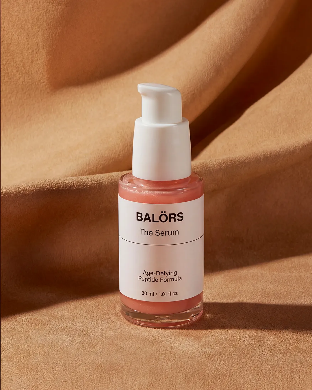 Frasco de Balörs The Serum sobre tela beige
